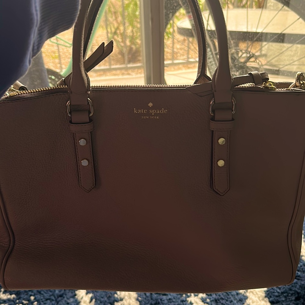 Nude color Kate Spade bag with strap.